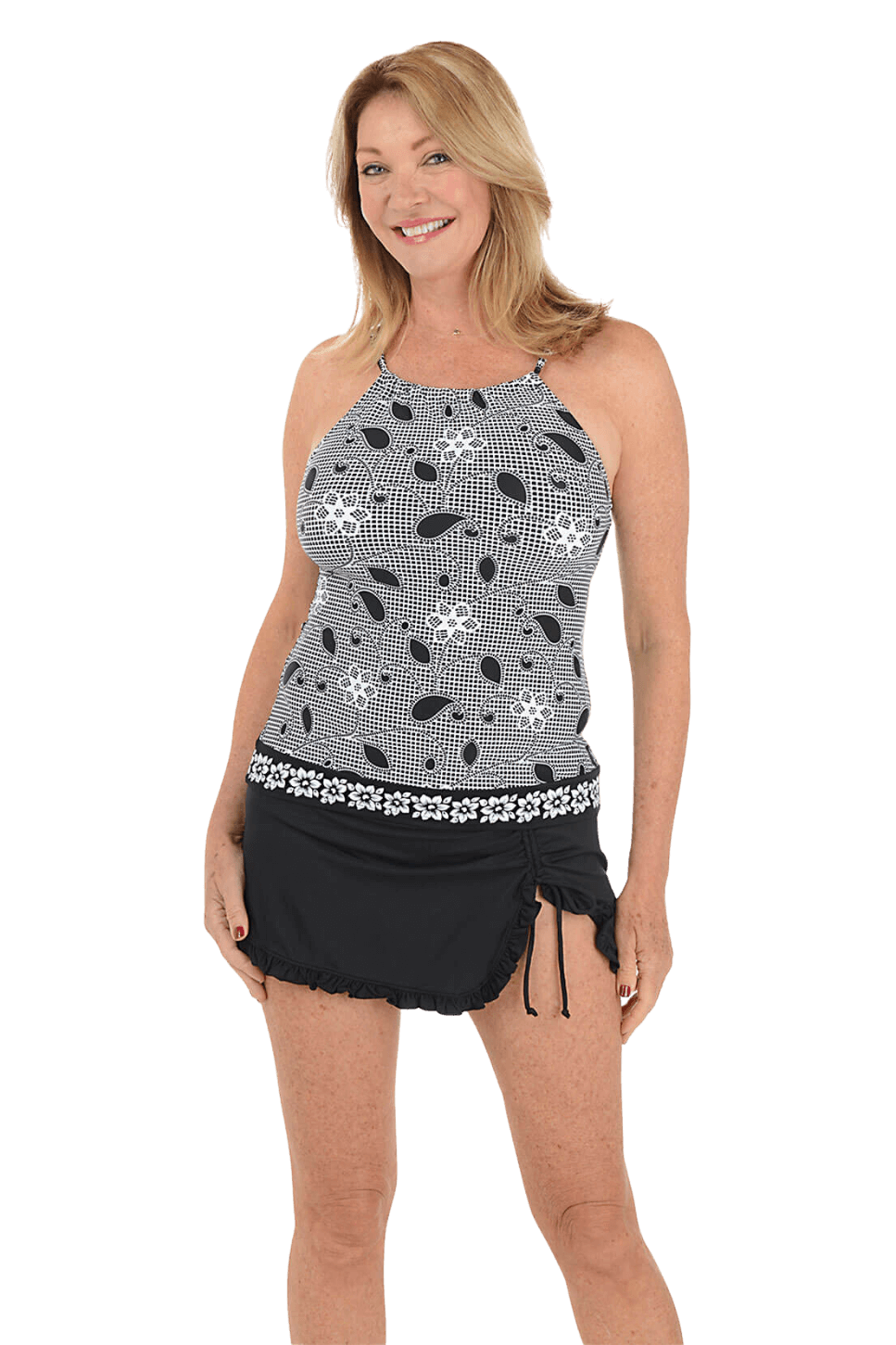 A woman wears a black and white printed tankini top and a black ruffled swim skort against a blue background