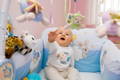 Baby in its crib, reaching towards a hanging fluffy toy.