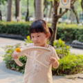 Little girl playing with a wooden bow and arrow set in the park. 