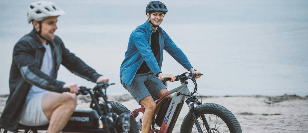 Two men riding electric bike on coast