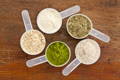 five scoops in a circle, each containing different dietary supplement powders, including collagen and wheat grass