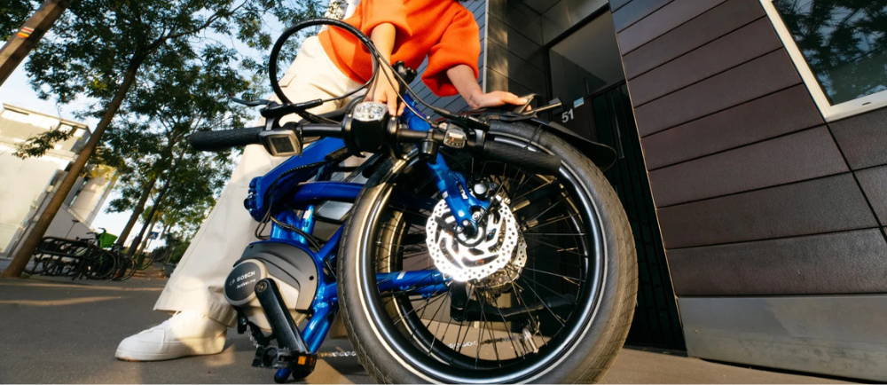 Woman with folding electric bike in folded position