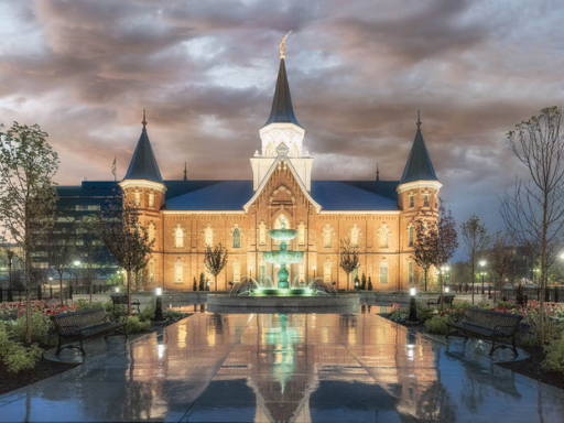 Provo City Center Temple glowing against a cloudy sky and reflected in the pavement.