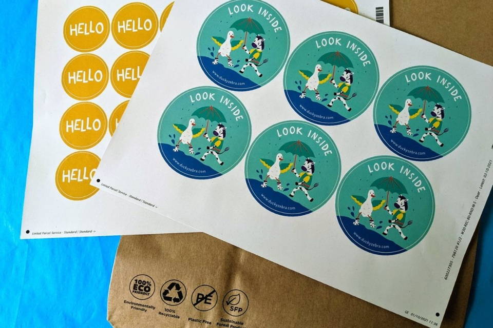 Image of Ducky Zebra packaging, including a brown paper postage bag, turquoise tissue paper and stickers