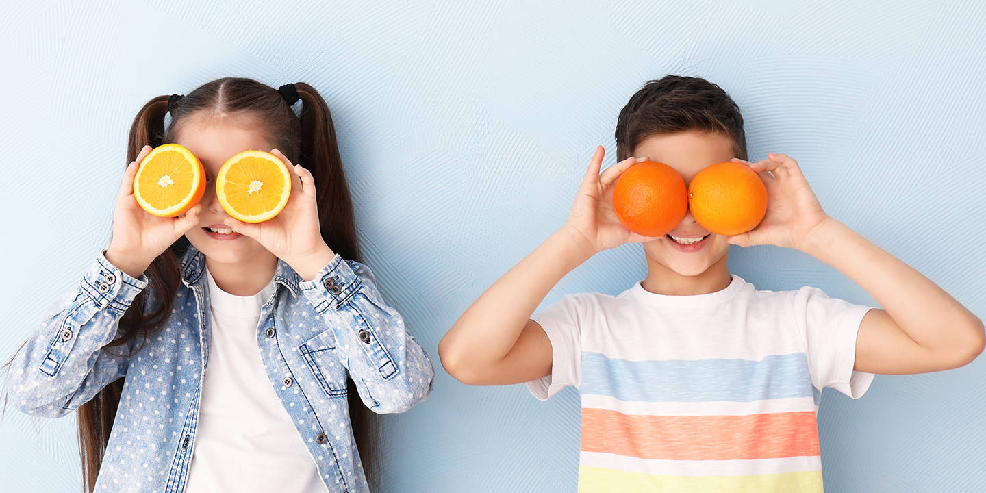 kids holding oranges up to their eyes.
