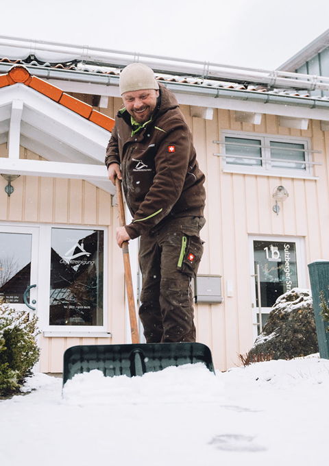 Mitarbeiter von Francesco's Hausmeisterservice beim Winterdienst vor einem Wohnhaus
