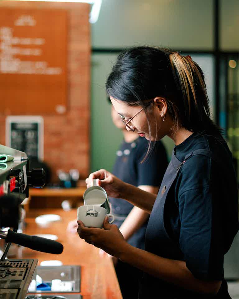 Female barista pouring coffee milk