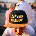 Man wearing a Love Your Neighbour flat brim cap