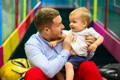 Father holding his son and talking to him while they are in the playroom.