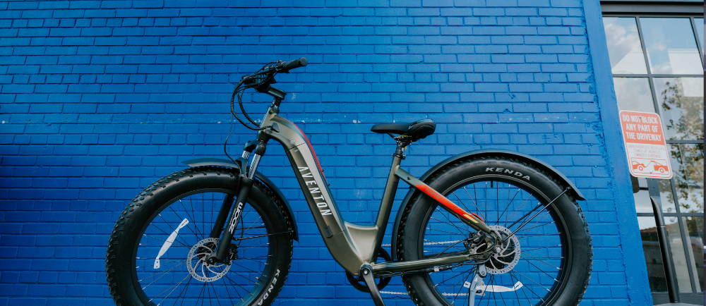 An Aventon Aventure e-bike next to a blue wall