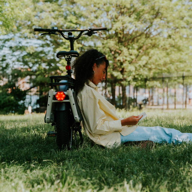 Rider leaning against electric bike in grass