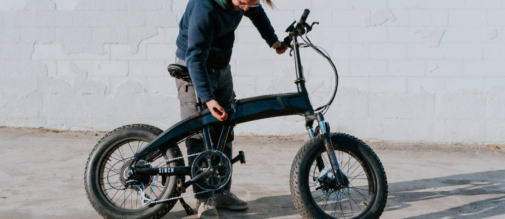 a man using the folding mechanism on an aventon sinch electric folding bike