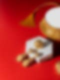 A gold choker necklace with a tassel, matching earrings, and a ring displayed on a red background alongside a white hexagonal stand.
