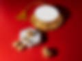 A gold choker necklace with a tassel, matching earrings, and a ring displayed on a red background alongside a white hexagonal stand.