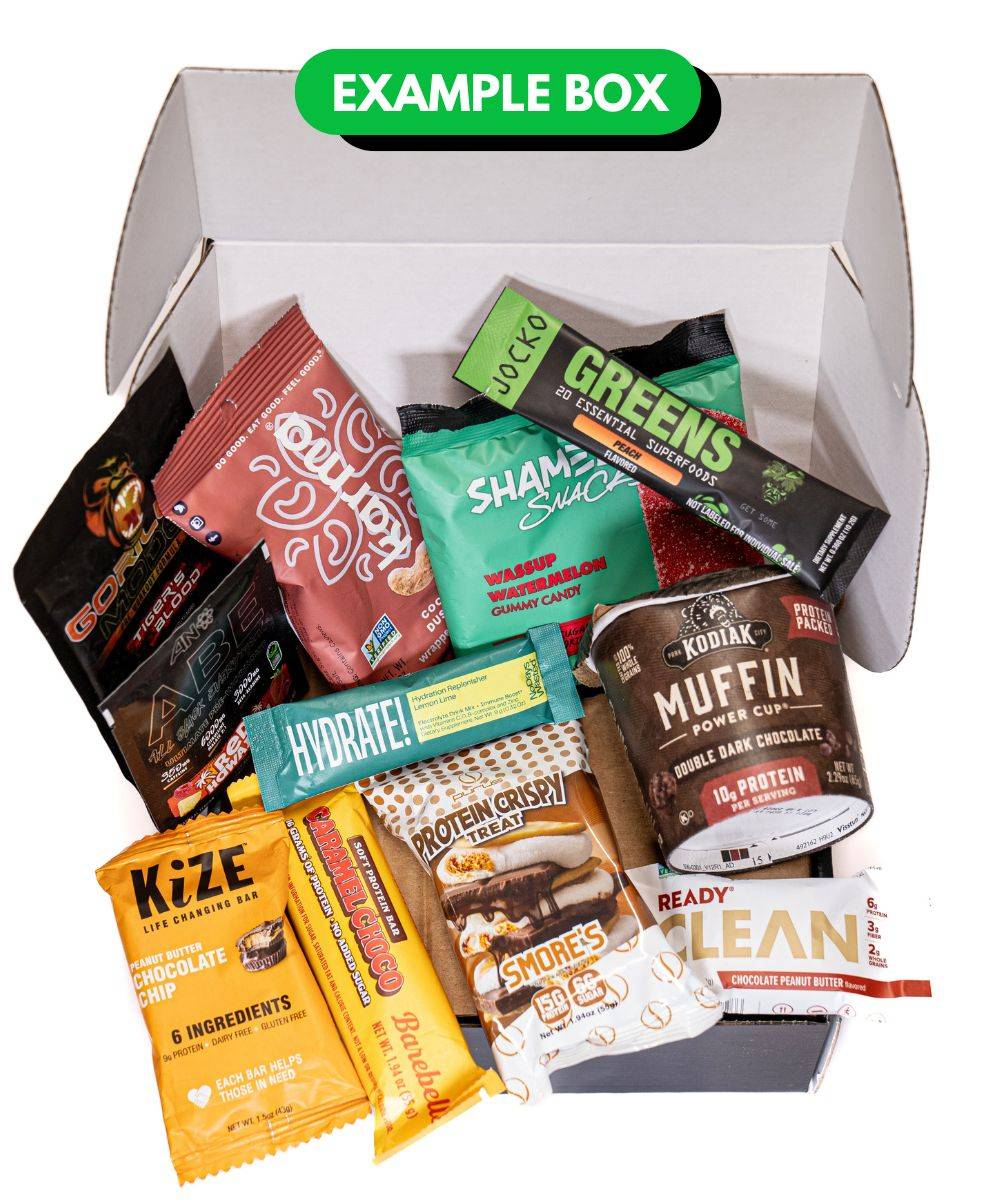 Fitness snacks and supplements displayed inside of a fitness subscription box featuring Kodiak oatmeal, Jocko greens, hydration powder, and more.