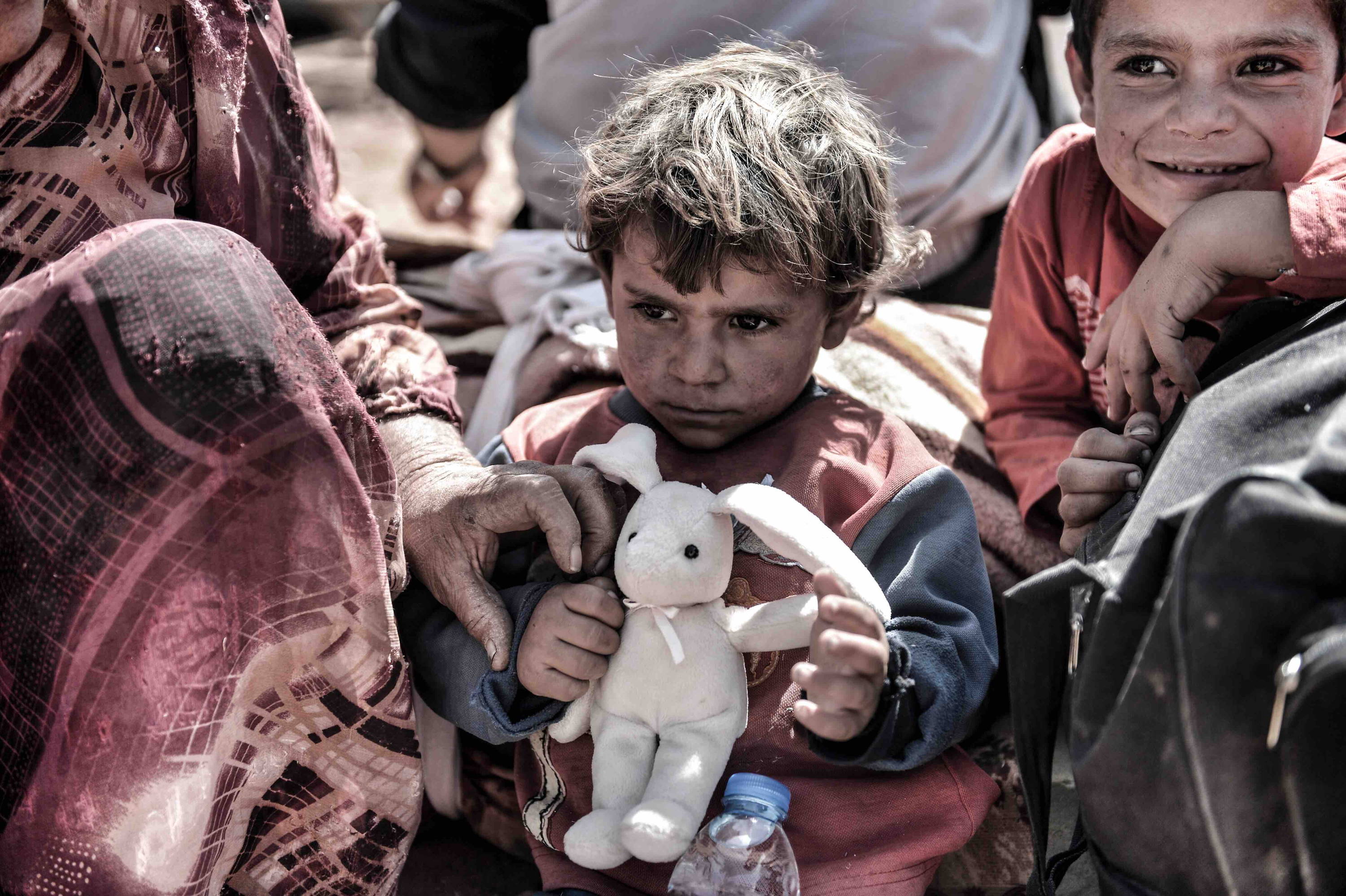 Syrian refugee boy clutching a teddy