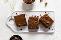Healthy chocolate protein brownies made with plant based pea protein on a grey background