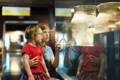 Mother showing an ancient artefact to her daughter in a museum. 