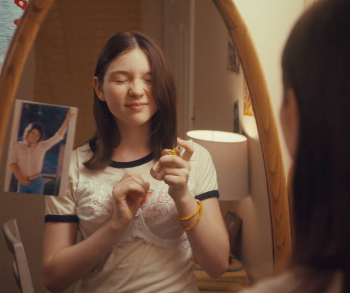 Young girl in front of mirror applying some Love's Baby Soft coologne on her. 