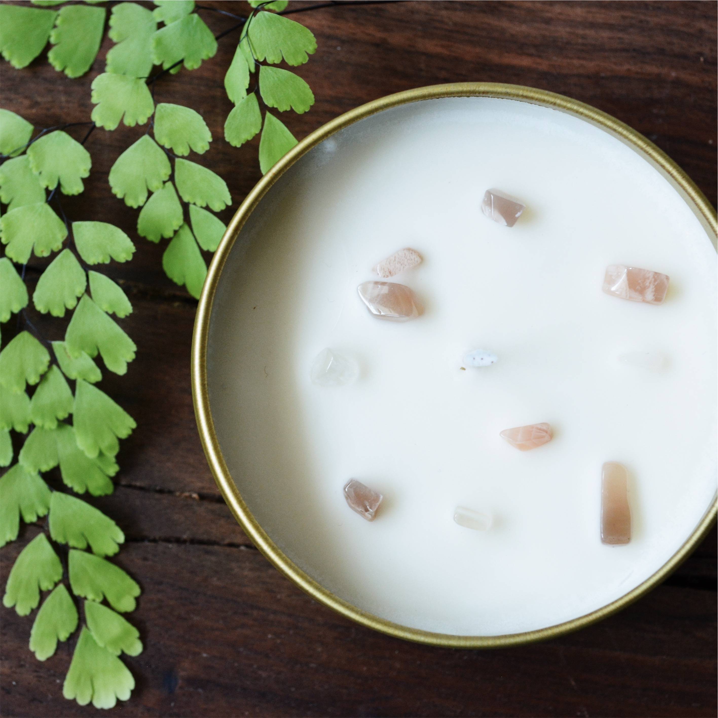 Summer Candle with moonstone chips on a table top with greenery