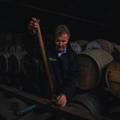 Homme goûtant du Whisky dans un chai traditionnel Dunnage Warehouse rempli de fûts de whisky en bois dans la distillerie Bruichladdich sur l'île d'Islay dans les Hébrides intérieures d'Ecosse