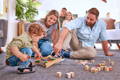 A mother and her toddler sitting on a playroom floor and playing with a colorful wooden Montessori hammering toy.