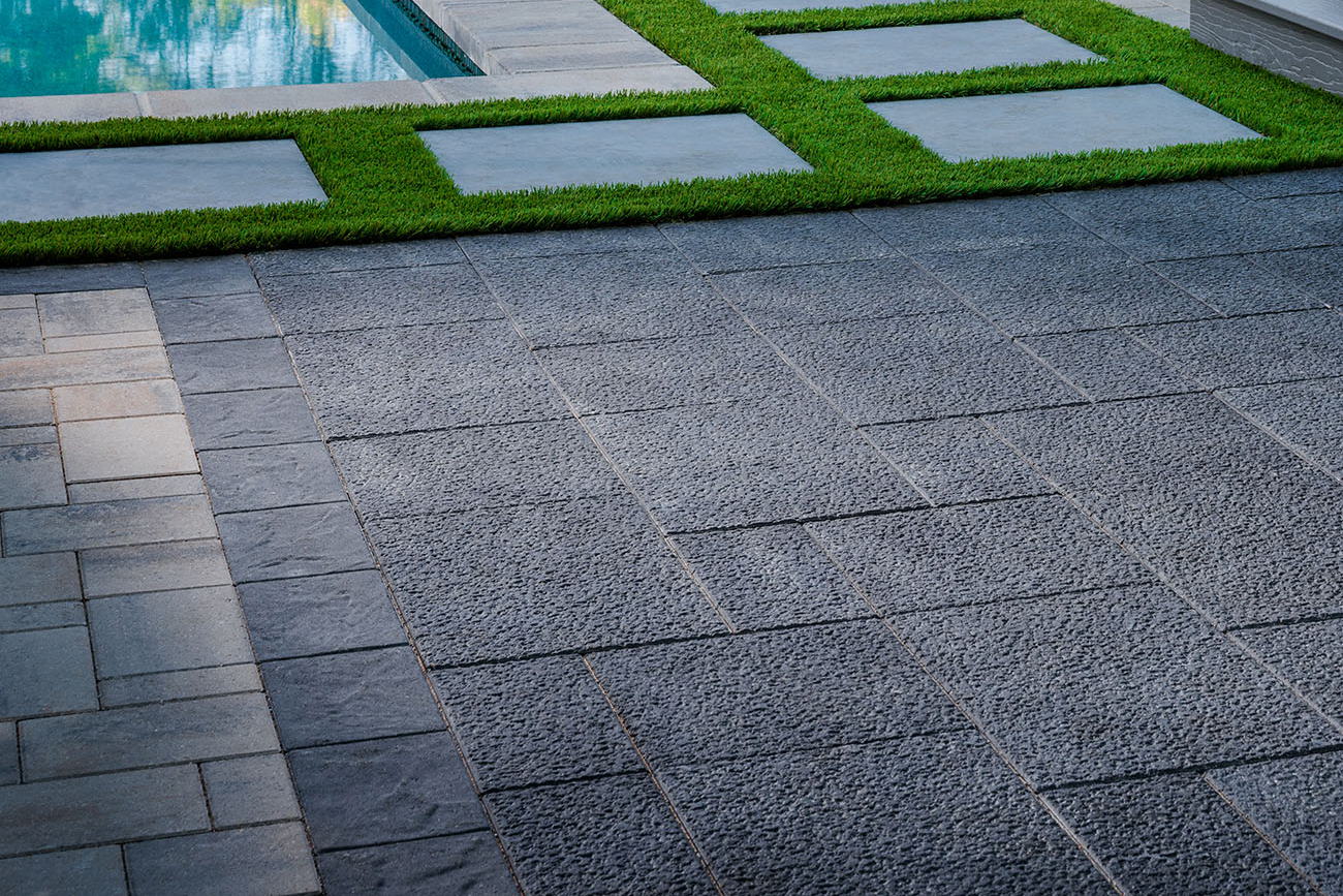 Patio made with basalt pavers with a pool in the background.