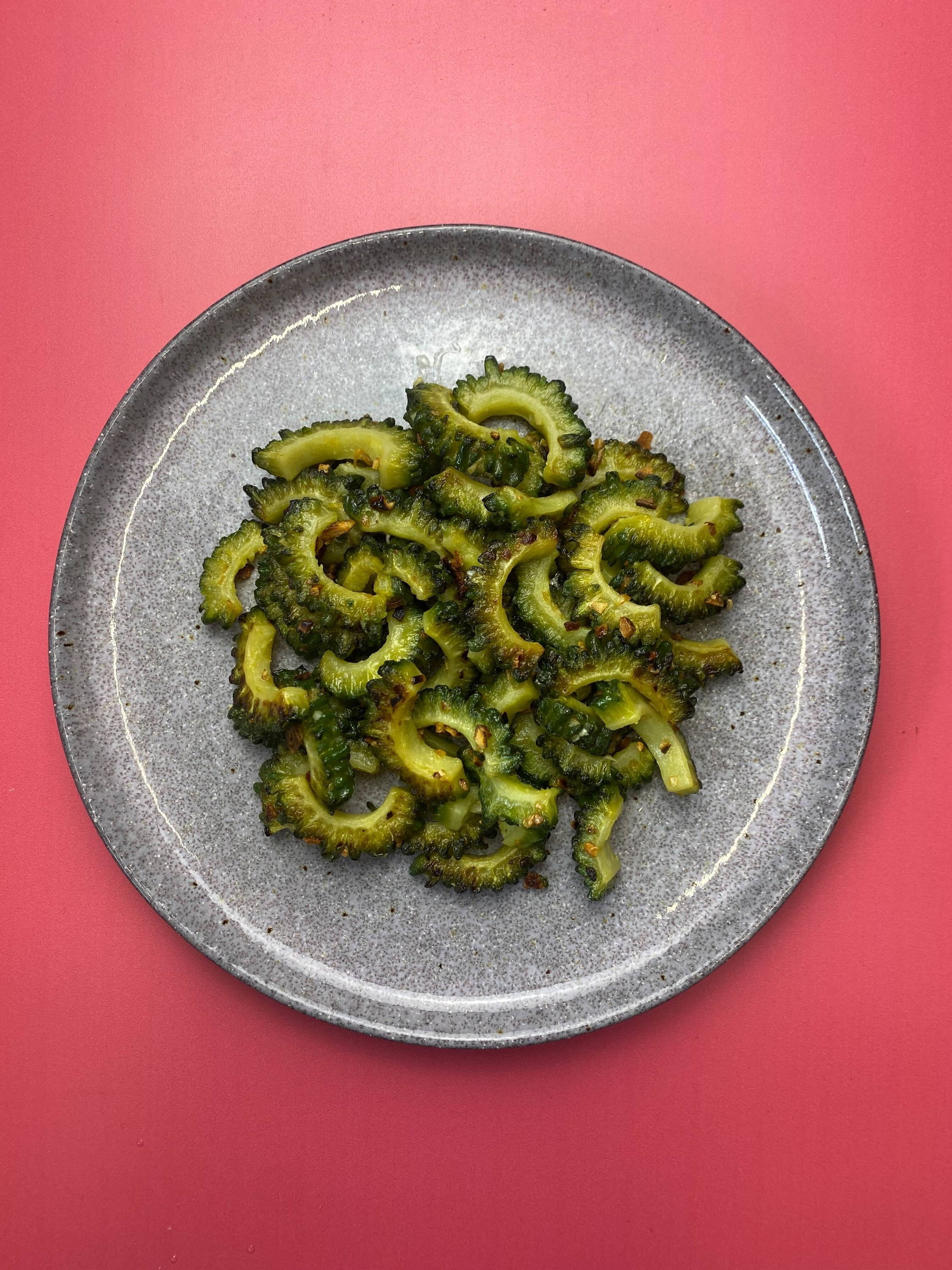 Fried bitter melon (karela), sliced on a plate.