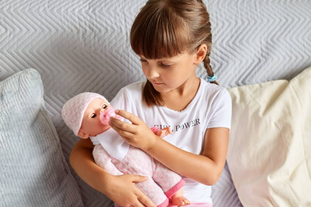 Little girl playing with a baby doll.