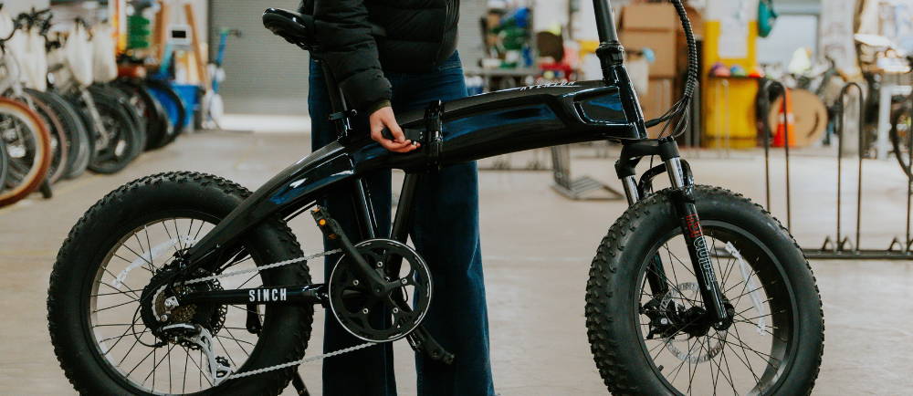 a woman using the folding switch on an aventon sinch electric folding bike