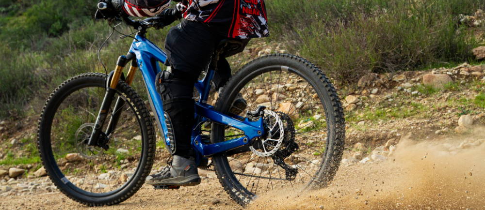 a person riding a blue full suspension electric mountain bike