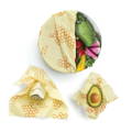 A bowl, a piece of cheese, and an avocado each individually wrapped partially in beeswax wraps