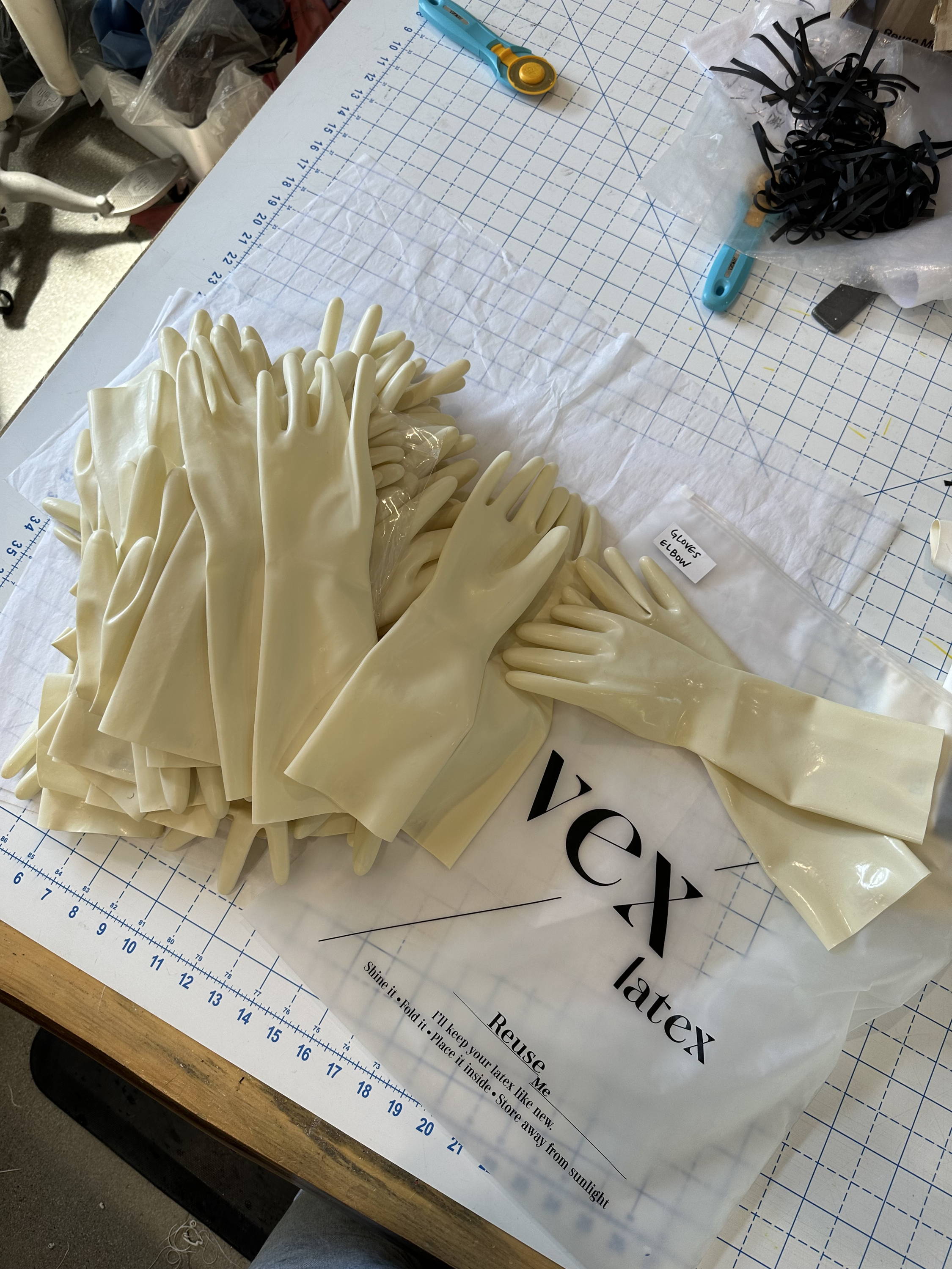 Ivory latex gloves handcrafted by Vex Clothing for Thom Browne fashion show, displayed on studio cutting table.