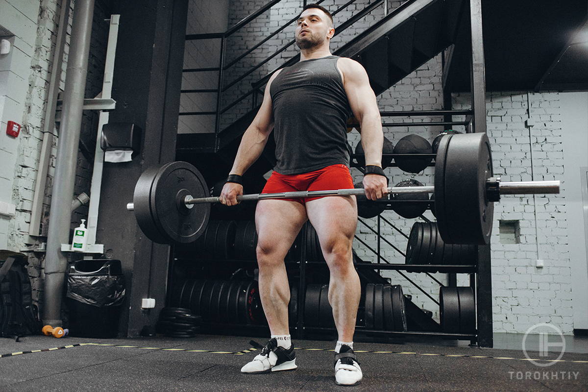 athlete in black shirt and red shorts training with barbell athlete in black shirt and red shorts training with barbell