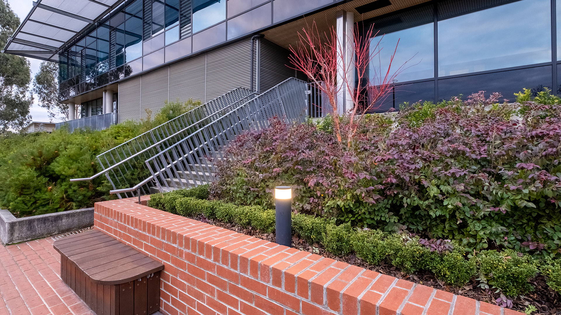 Closeup view of a Havit Commercial Bollard LED Light situated in one of the garden beds of Luther College