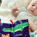 Baby laying on her back and looking at the Montessori Baby Soft Book.