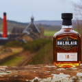 Bouteille de Single Malt Scotch Whisky Balblair 18 ans posée sur un muret à côté de la distillerie Balblair dans les Highlands du nord-ouest d'Ecosse