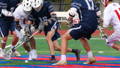Lacrosse players on the field in the middle of a play.