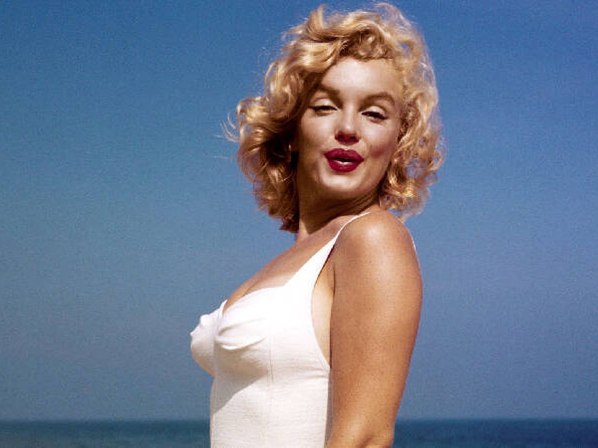 Marilyn Monroe posing blowing a kiss to the camera while at the beach.