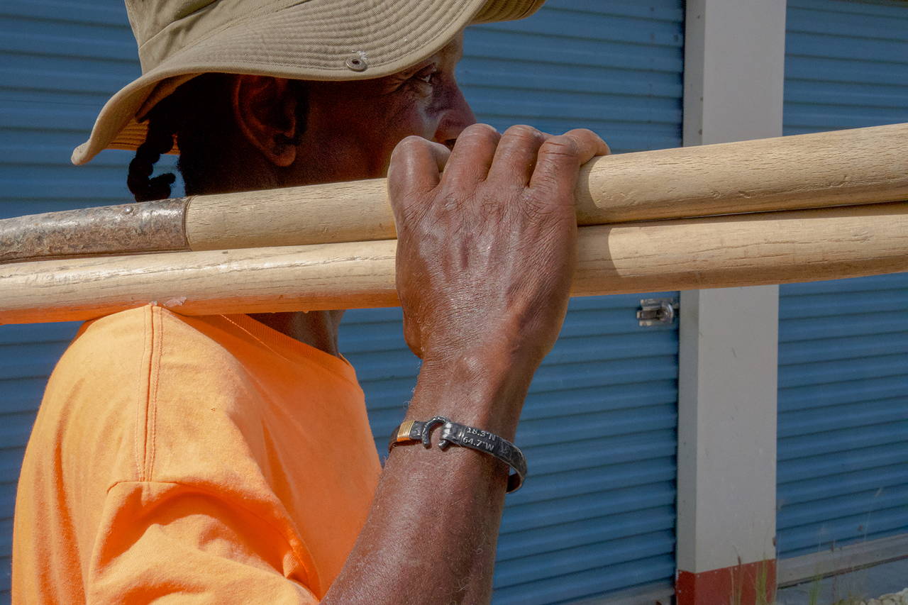 Working man carrying a shovel and wearing a Vibe Jewelry Caribbean hook bracelet.