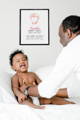 black father and baby playing with personalized baby footprint birth day keepsake on wall behind