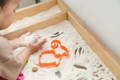 Toddler playing with sand in a wooden box. 