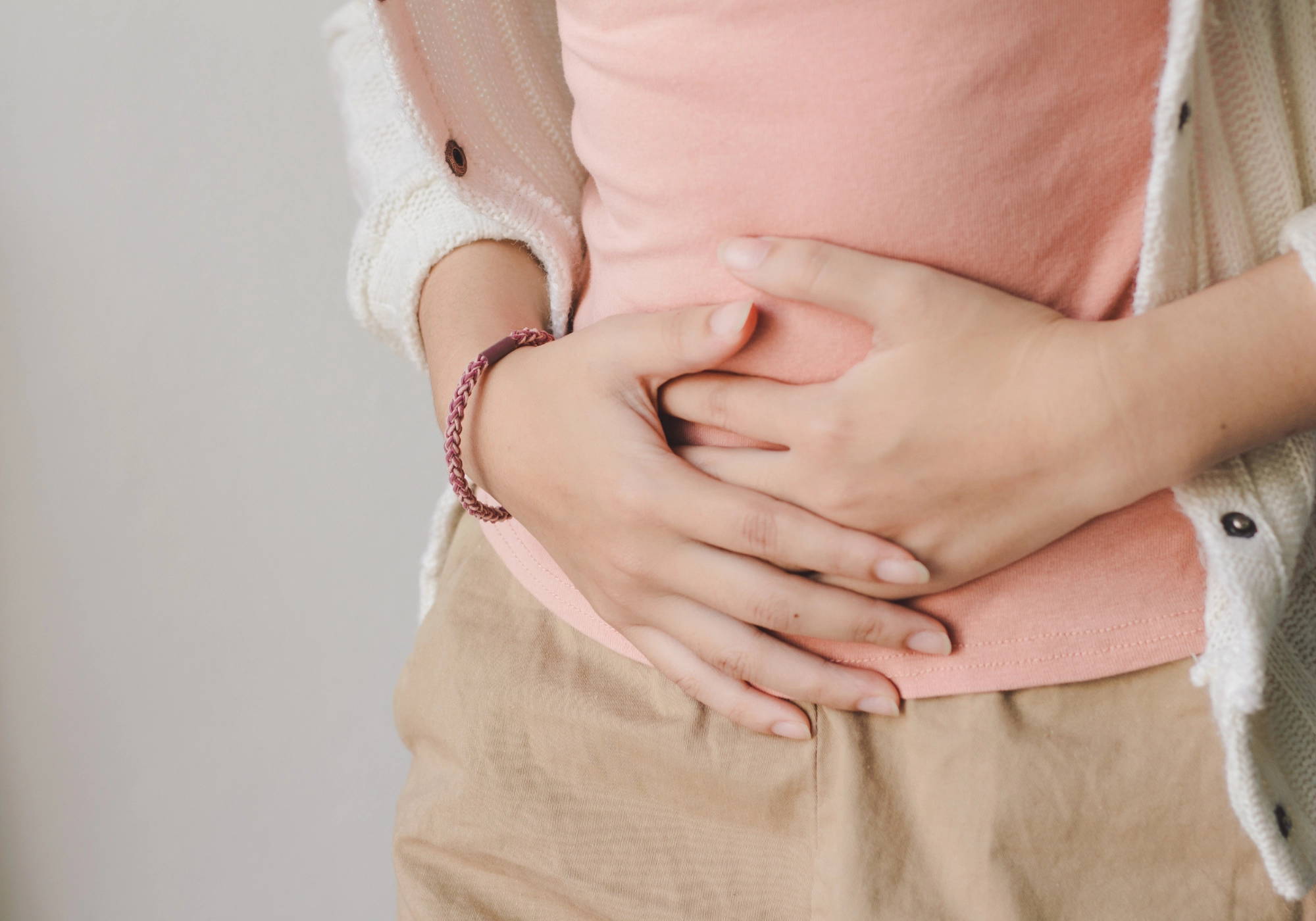 Woman experiencing abdominal discomfort while holding her stomach.