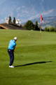 Golfer executing a precise chip shot toward the red flagstick on the green