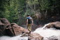 man walking on the rocks next to the top of a waterfall wearing a devils kettle daypack