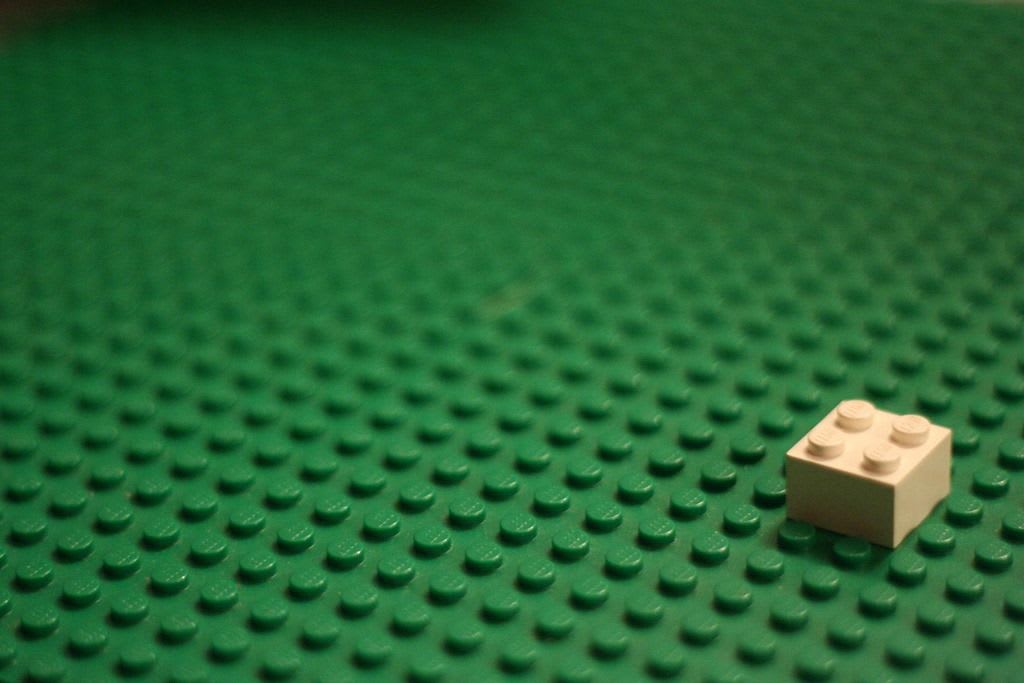 a single yellow lego block on a green base