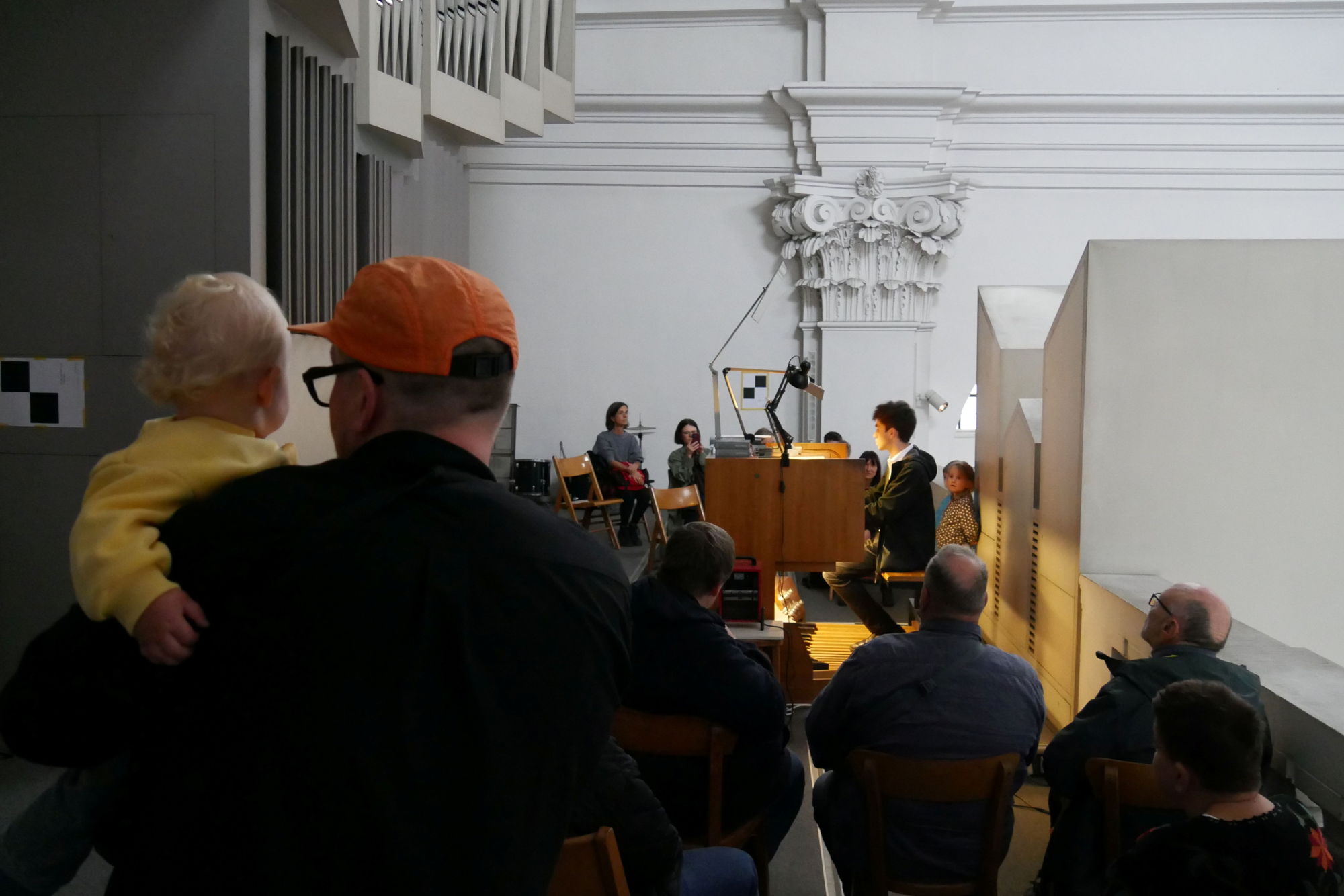 Ein Mann musiziert auf einer Orgel vor Publikum. 