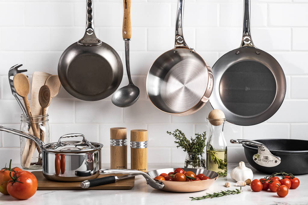 A kitchen with pots, pans, herbs, and vegetables.