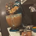 A kitchen aid mixer in kitchen with many glass spice jars skewed around it