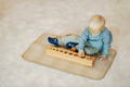 Little boy sitting and playing with a wooden Montessori shapes toy. 